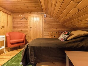 Une pièce dans un chalet en bois, comprenant un lit, une chaise et une commode.