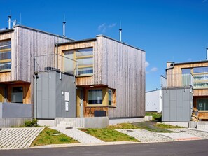 Un edificio moderno con fachada de madera, múltiples ventanas y techo plano.