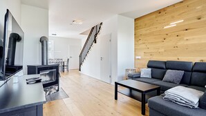 A modern living room with a sofa, coffee table, TV, and fireplace. - Ore house by Interhome (Loucna pod Klínovcem)