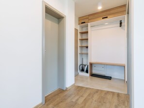 Un armario moderno con estantes de madera, un aspirador y un banco.