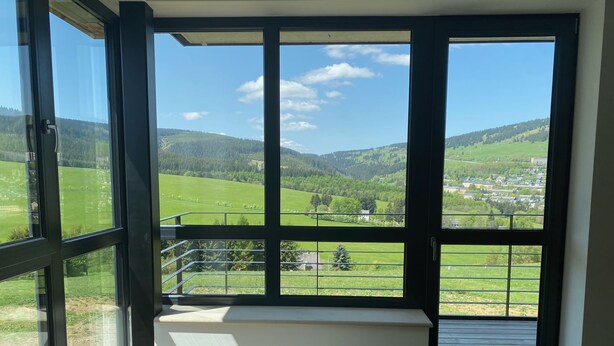 Ein Zimmer mit einem großen Fenster und Blick auf eine grüne Landschaft und Hügel.