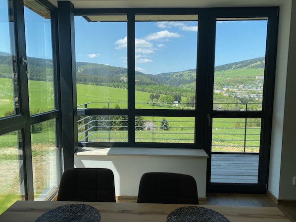 Una habitación con un amplio ventanal que ofrece vistas a un paisaje verde y colinas.