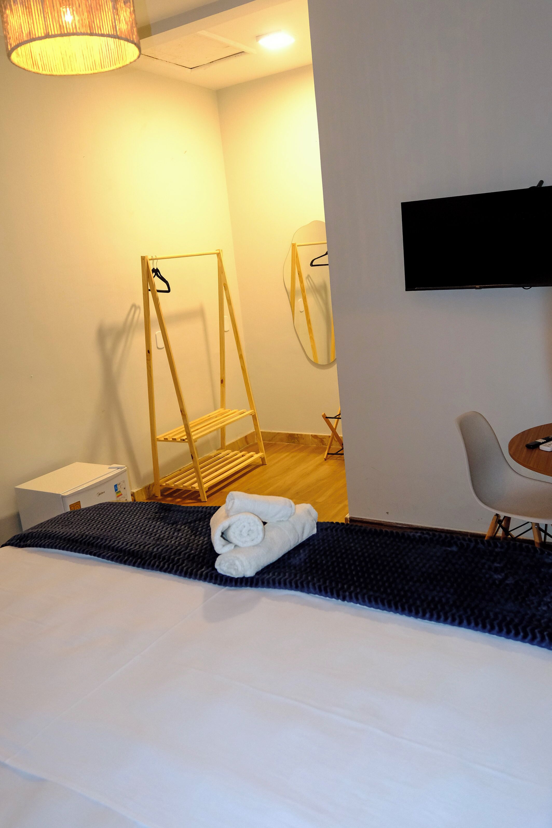 A hotel room with a bed, a TV mounted on the wall, a small table, and a chair.