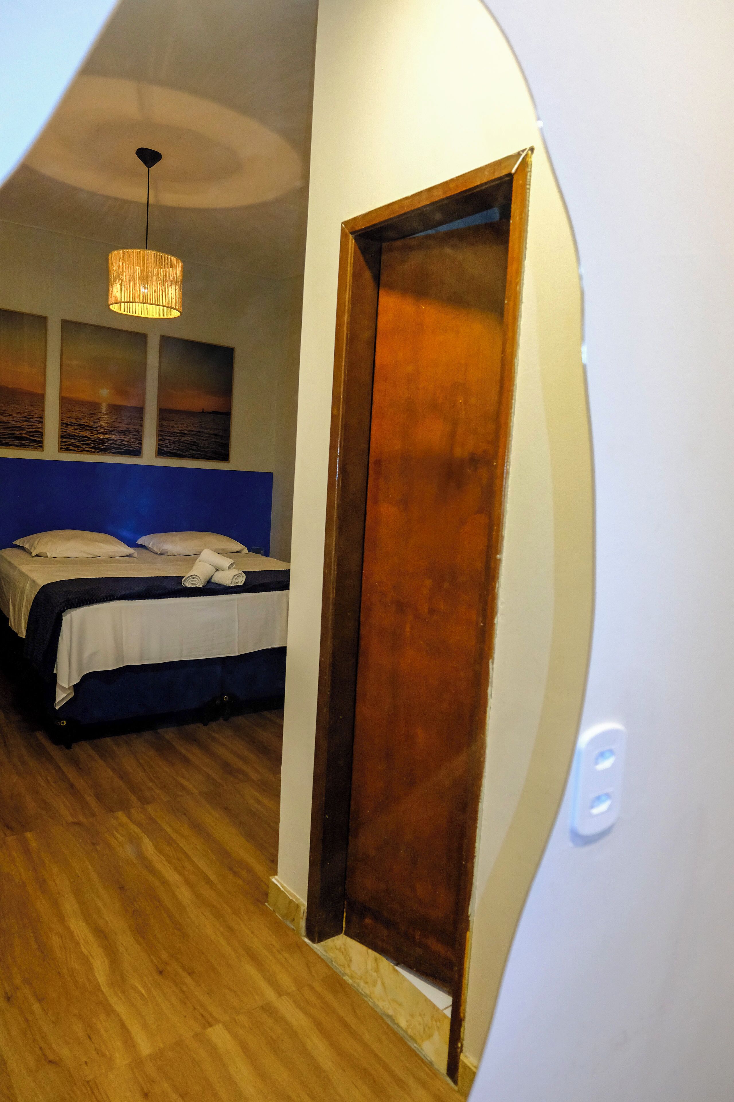 Une chambre à coucher avec un lit, une porte en bois et un luminaire suspendu.