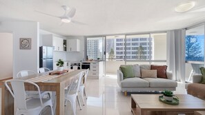 Un appartement moderne comprenant un coin repas, une cuisine et un espace de vie doté de grandes fenêtres.