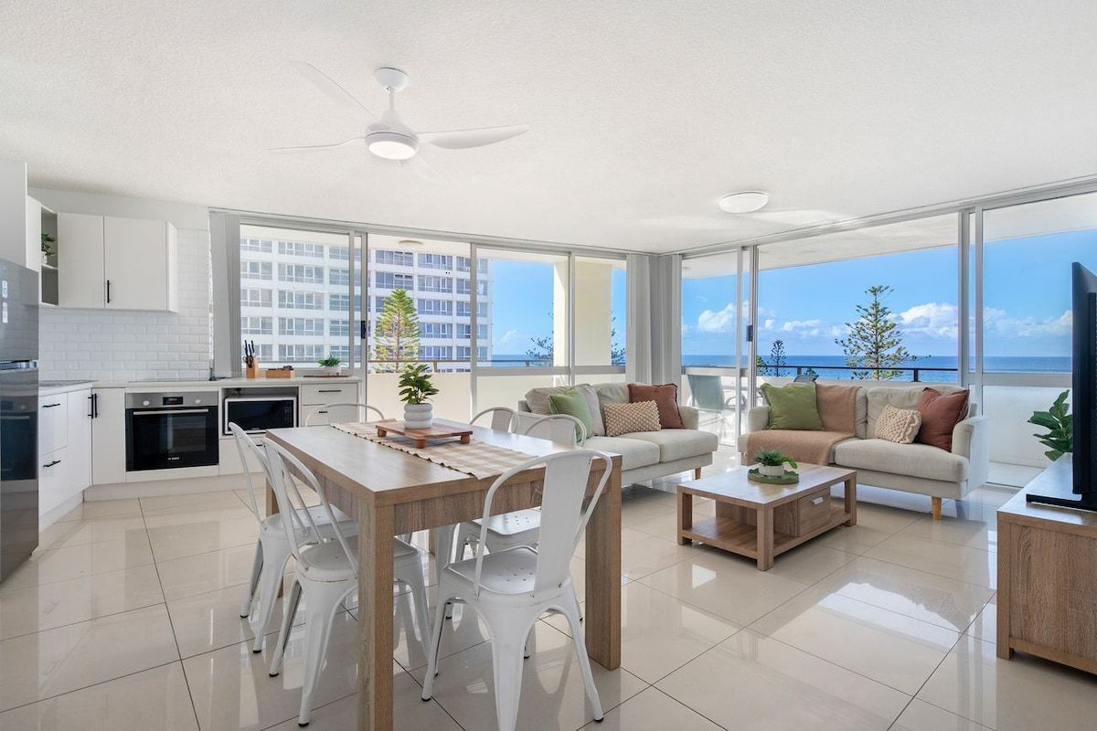 A modern apartment with a kitchen, dining area, and living room with large windows.
