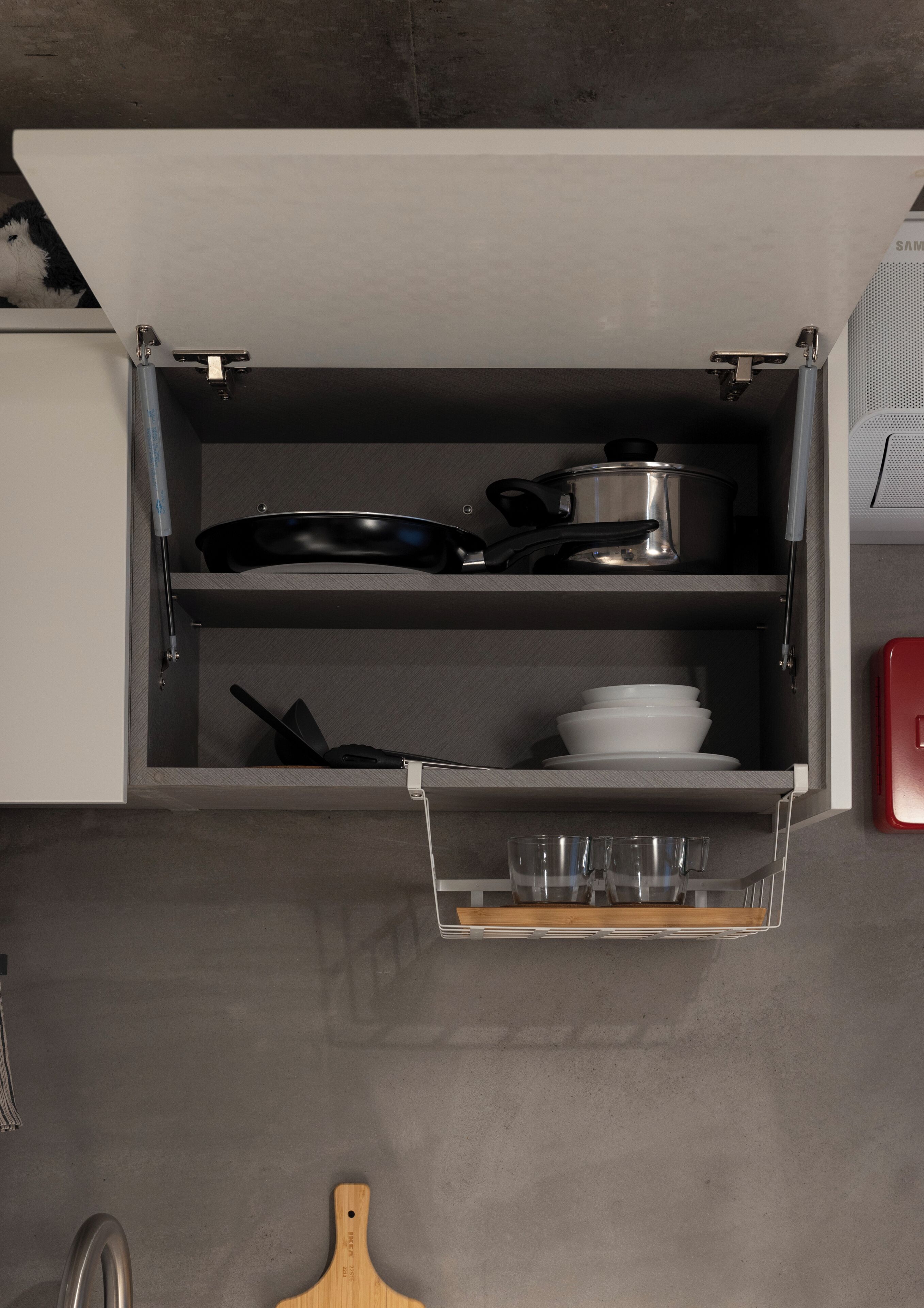 A kitchen with a built-in drawer containing cookware, plates, and glasses.