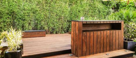 A wooden deck with a built-in bench and a planter with a plant.