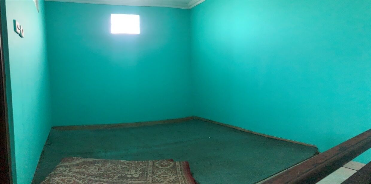 A room with teal walls, a small window, and a carpeted floor.
