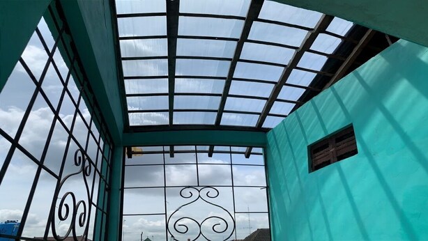 A room with a skylight, a window with decorative ironwork, and a teal wall. - Bronk House (Yogyakarta)