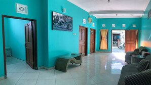 A teal-walled room with a sofa, a bench, and a motorcycle-themed painting. - Bronk House (Yogyakarta)