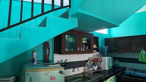 A kitchen with teal walls, a refrigerator, a sink, and wooden cabinets. - Bronk House (Yogyakarta)