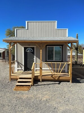 A small, single-story building with a covered porch and a door. - Westworld Cabins (Quartzsite)