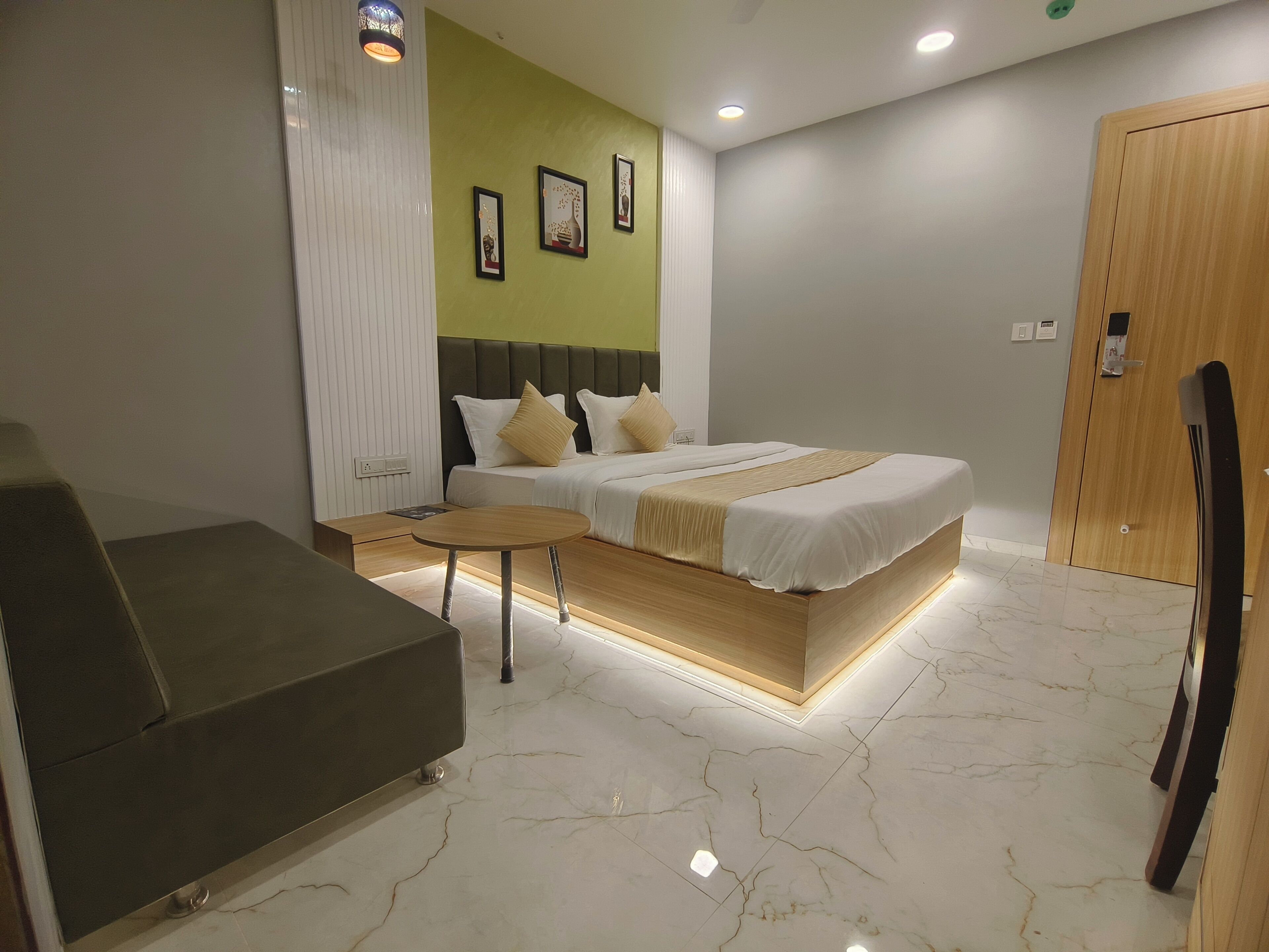 A modern hotel room with a bed, bedside tables, a sofa, and a wooden wardrobe.