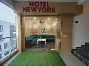 A hotel entrance with a reception desk, a green sofa, and a small table.