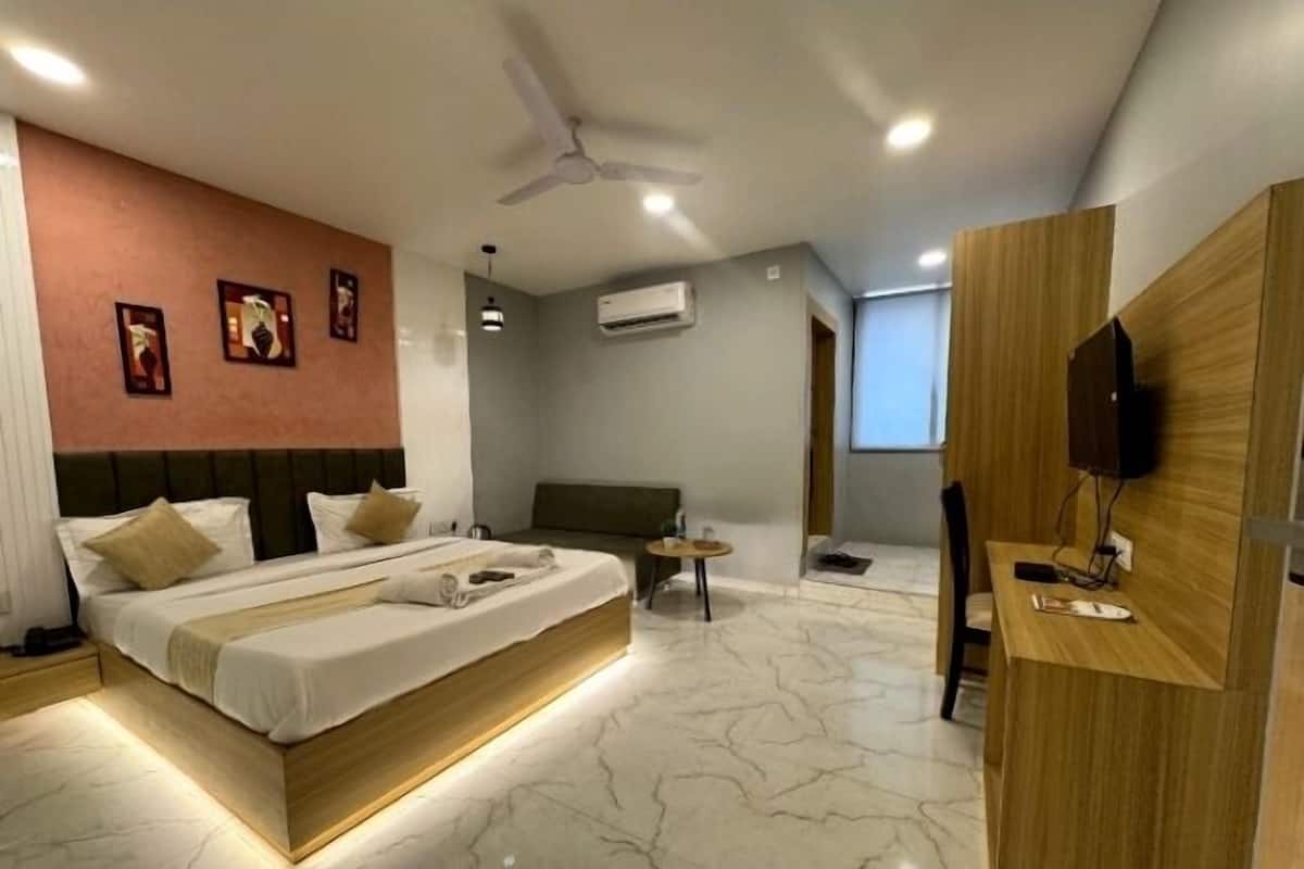 Una habitación de hotel moderna con una cama grande, un escritorio y un televisor.
