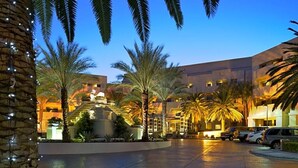 Un patio de hotel con palmeras, un paseo techado y una zona de estacionamiento.