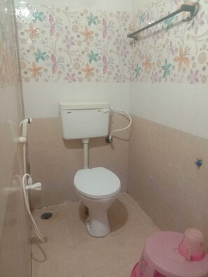 A small, enclosed bathroom with a toilet, a shower area, and a sink.