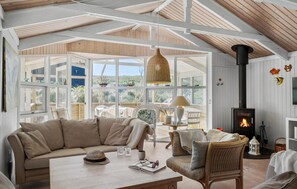A cozy living room with a large window, a fireplace, and a comfortable seating area. - 3 bedroom beautiful home in Blokhus (Blokhus)