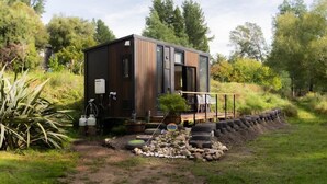 Eine moderne Holzhütte mit Terrasse und Gartenbereich mit Steinen und Pflanzen.