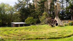 Ein Labyrinthgarten mit einem kleinen Gebäude und einem Tipi inmitten von Bäumen.