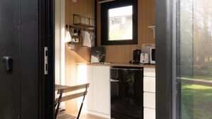 Eine kleine Küche mit Fenster, einer Kaffeemaschine und einer Mikrowelle.