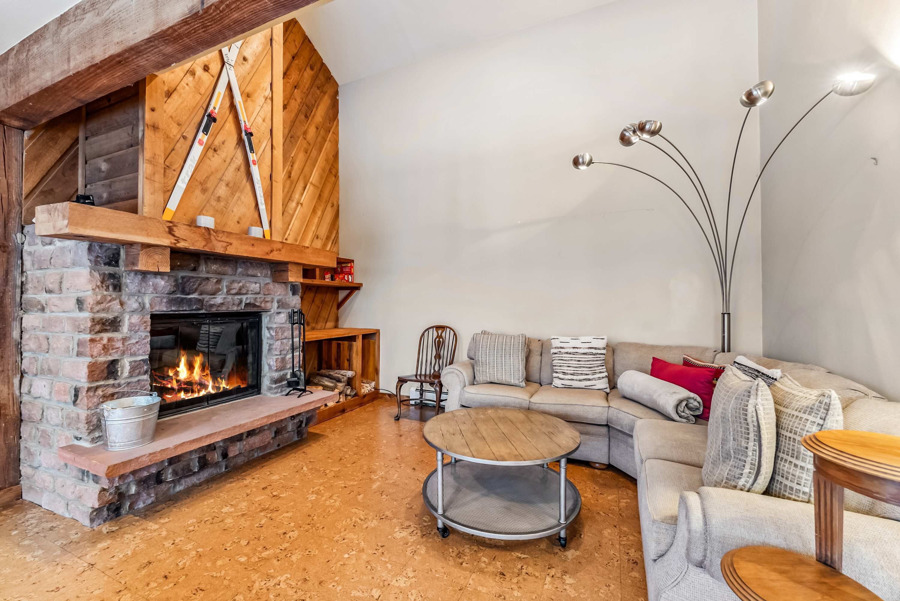 A cozy living room with a stone fireplace, a wooden ceiling, a sofa, and a coffee table.