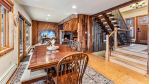 A dining area with a wooden table and chairs, a fireplace, and a staircase. - Dillon Retreat with Lake Views and Private Hot Tub (Dillon)
