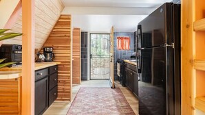A modern kitchen with wooden accents, a built-in oven, and a large refrigerator. - Cozy A-Frame High in The Tree Tops (Crestline)