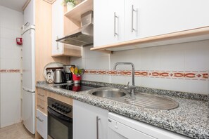 Eine Küche mit Edelstahlspüle, Granitarbeitsplatte, weißen Schränken und einem eingebauten Ofen.