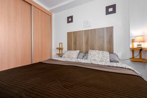 Una camera da letto con un letto, una testiera in legno, comodini e un tavolino da notte.