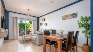 Una sala de estar moderna con comedor, sofá, mesa de centro y vistas al exterior.