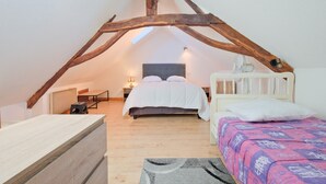 A bedroom with a sloped ceiling, a bed, a bedside table, and a chair. - Le Pressoir – Authentic Cottage in the Heart of Périgord Noir, Perfect for Families & Friends (Salignac-Eyvigues)