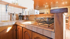 A kitchen with wooden cabinets, a sink, a coffee maker, and a hanging basket. - Le Pressoir – Authentic Cottage in the Heart of Périgord Noir, Perfect for Families & Friends (Salignac-Eyvigues)