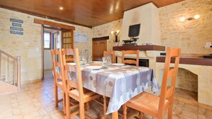 A dining area with a table set for four, wooden chairs, a stone wall, and a wooden ceiling. - Le Pressoir – Authentic Cottage in the Heart of Périgord Noir, Perfect for Families & Friends (Salignac-Eyvigues)