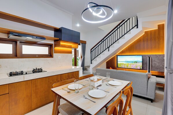 A modern kitchen with a built-in stove, wooden cabinets, and a dining area with a table set for four.