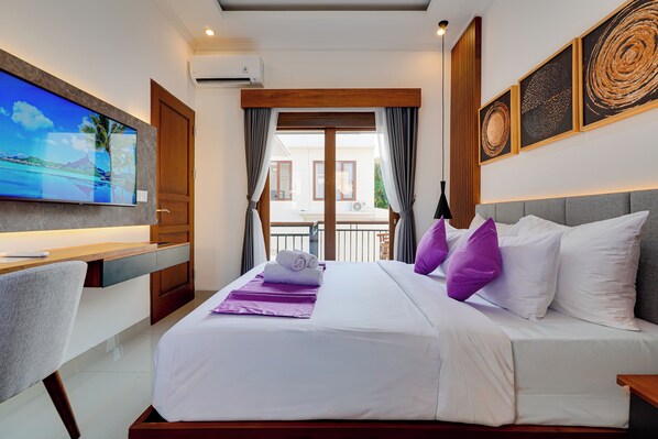 A hotel room with a bed, a desk, a TV, and a balcony view.