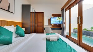 A hotel room with a bed, a television, a desk, and a view of an outdoor pool. - Villa Prinz near Nusa Dua Beach (Nusa Dua)