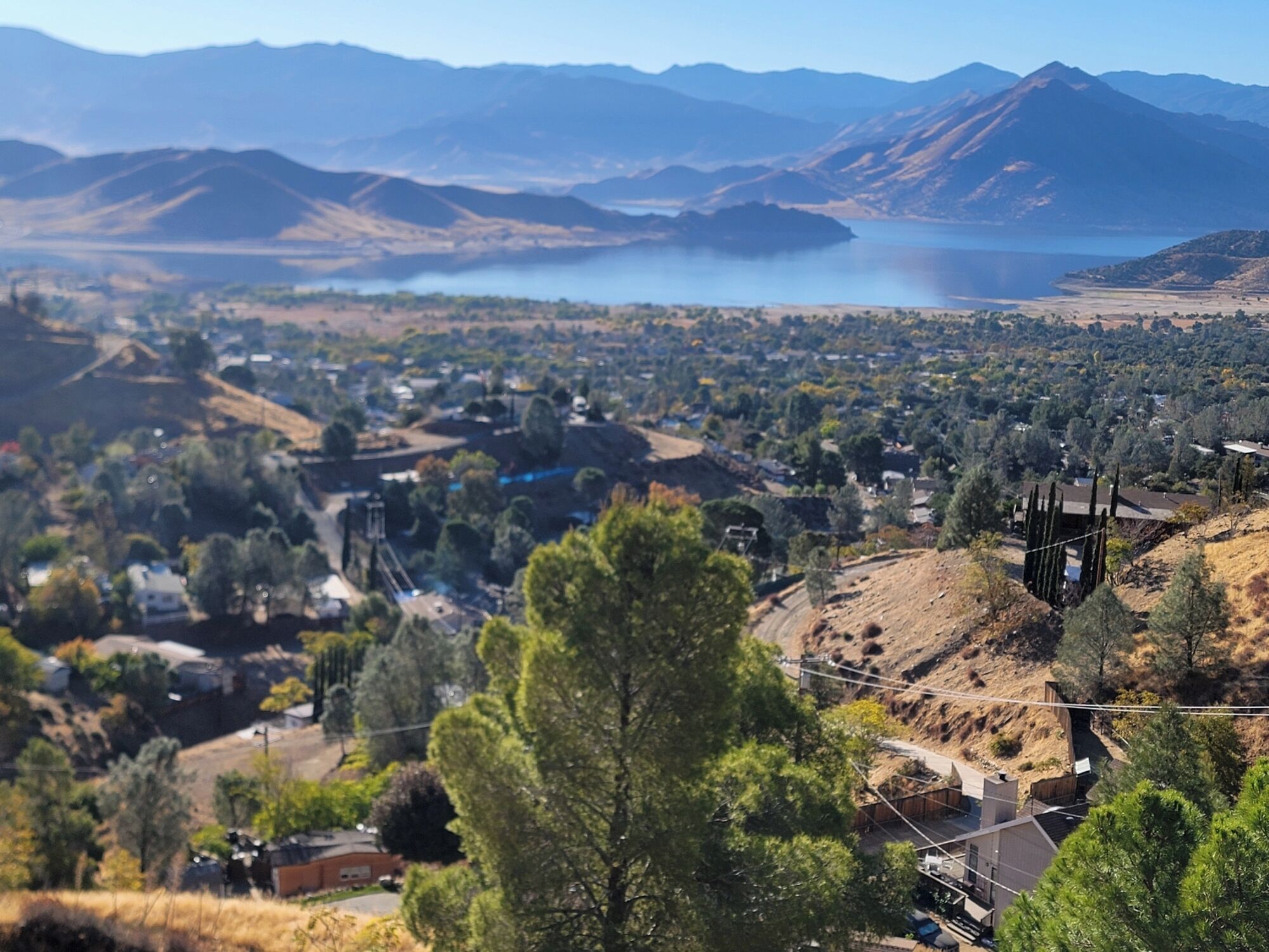 A panoramic view of a town with a lake, mountains, and a mix of residential and commercial buildings.