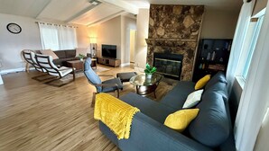 A modern living room with a stone fireplace, a large sofa, and a television.