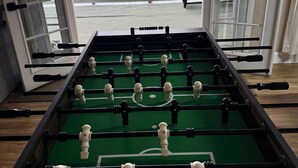 A foosball table with a scenic mountain view through open doors.