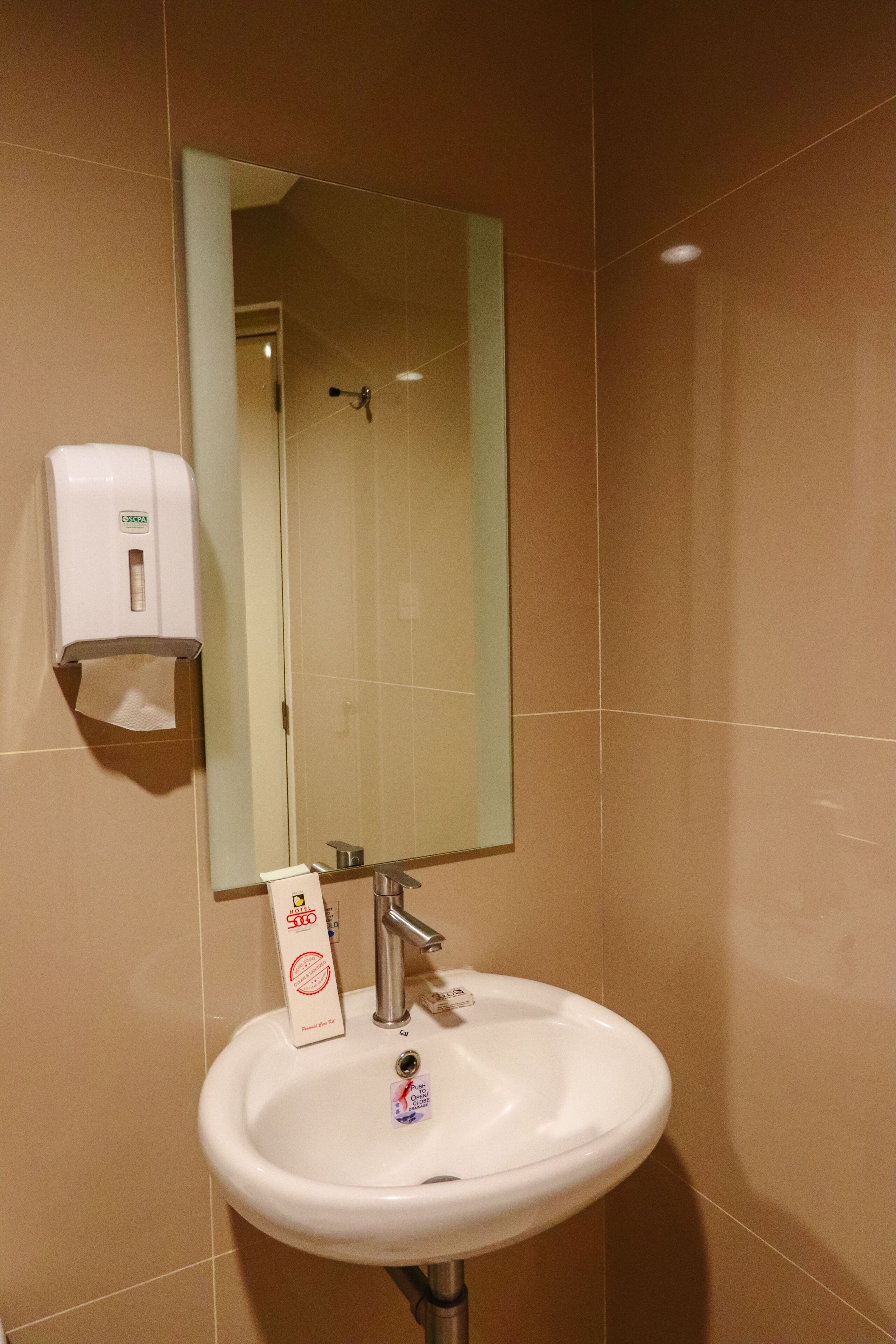 Un baño con lavamanos blanco, espejo y dispensador de jabón.