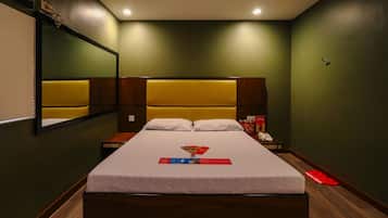 A hotel room with a large bed, a bedside table, a mirror, and a nightstand.