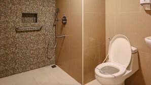 Une salle de bain équipée d’une douche, de toilettes et d’un sèche-mains.