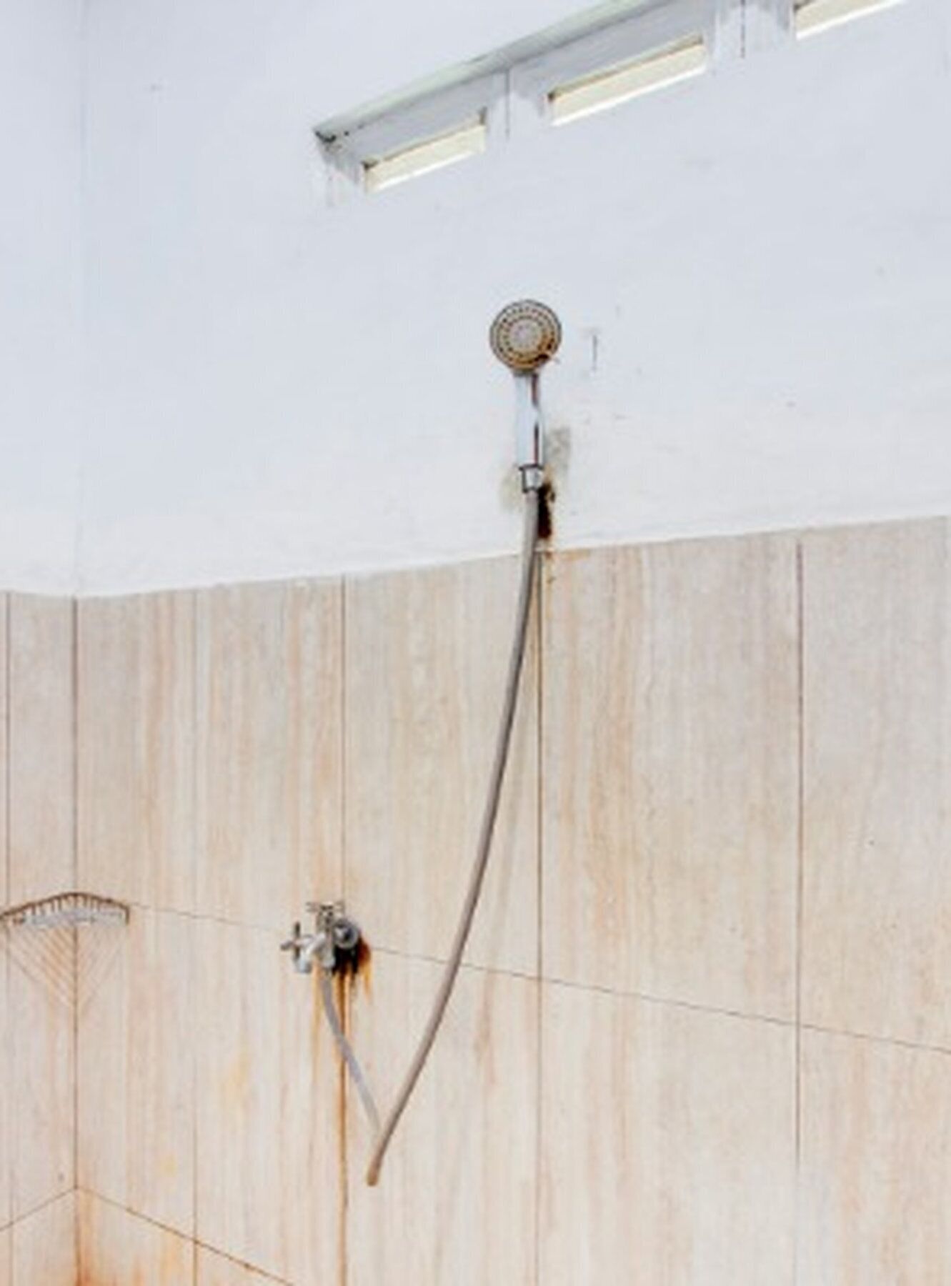 A shower with a handheld showerhead and a wall-mounted control valve.