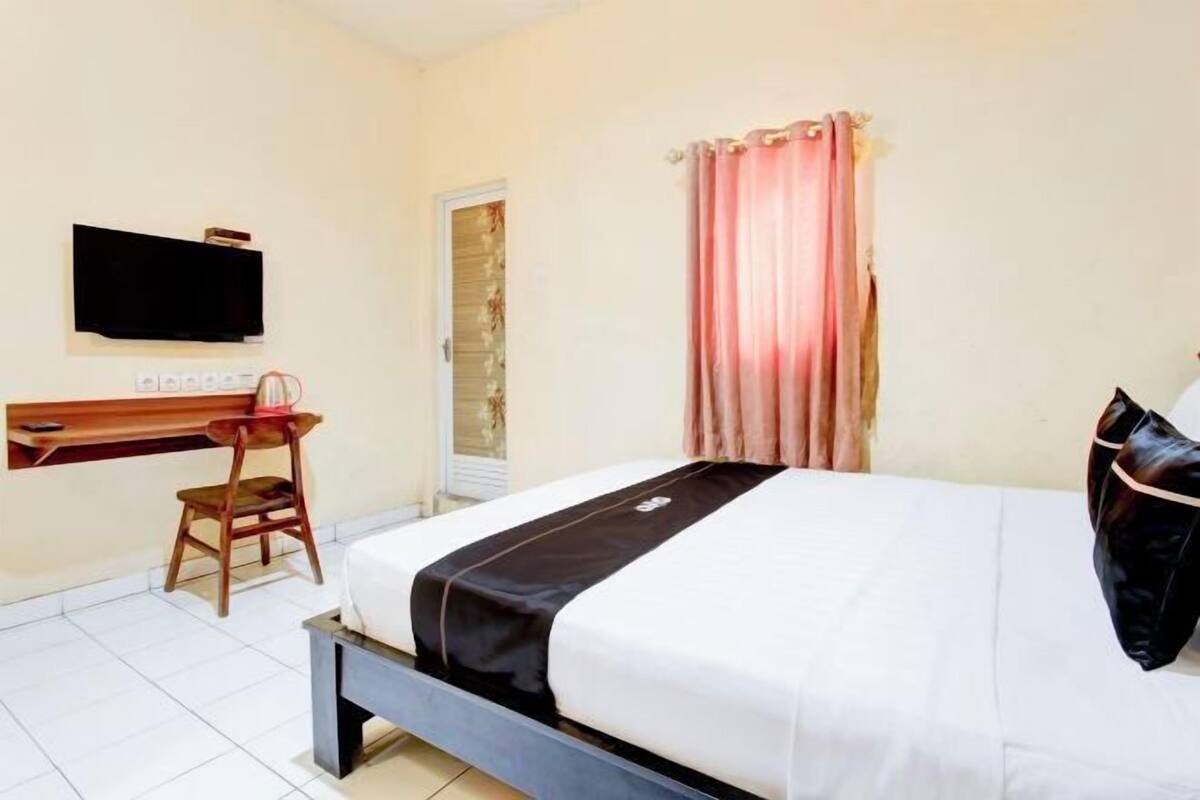 Ein Hotelzimmer mit Bett, Schreibtisch, Stuhl, Fernseher und einer Tür.