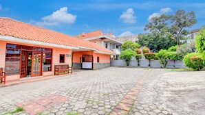A courtyard with a tiled floor, a building with a red-tiled roof, and a bench. - Collection O Stasiun Pekalongan Near Stasiun Kereta Api Formerly Hotel Indah (Pekalongan)
