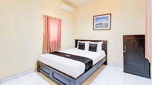 A bedroom with a bed, a wardrobe, a picture on the wall, and a window with curtains. - Collection O Stasiun Pekalongan Near Stasiun Kereta Api Formerly Hotel Indah (Pekalongan)