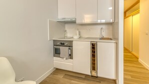 A modern kitchen with white cabinetry, a built-in oven, a sink, and a small countertop.