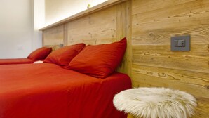 A wooden headboard with a light switch, a red bedspread, and a white fluffy footrest. - Private room with mountain view, shared terrace and Wi-Fi (Pont-Saint-Martin)